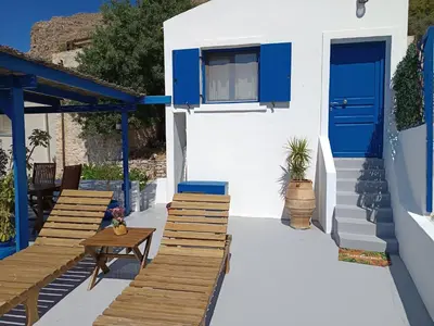 a patio with blue doors and wooden benches at IVISKOS House, Megalo Horio village, Tilos Island in Megálon Choríon