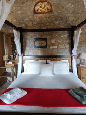 a bedroom with a large bed with a red blanket at ILAKATI House, Megalo Horio village, Tilos Island in Megálon Choríon