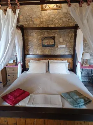 a bedroom with a large white bed with curtains at ILAKATI House, Megalo Horio village, Tilos Island in Megálon Choríon