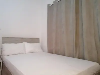 a bed with white sheets and pillows in a bedroom at Jz Plus Classio in Rhodes Town