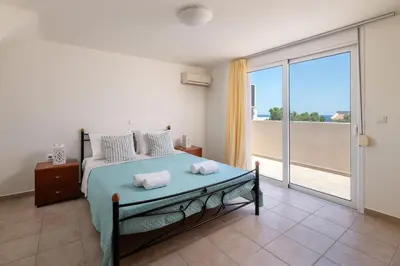 a bedroom with a bed and a large sliding glass door at Lindos Villa Fadia with Private Pool in Líndos