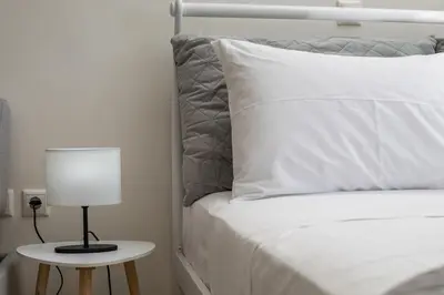 a bed with a white pillow and a lamp on a table at Economisa Apartments in Ialyssos