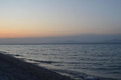 a sunset over the ocean with a beach at Economisa Apartments in Ialyssos