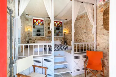 a bedroom with a bed and a desk and chairs at Aphrodite Villas Halki - Studio Rosa in Halki