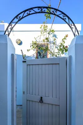 a white gate with an arch with a plant at Aphrodite Villas Halki - Studio Rosa in Halki