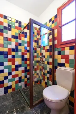 a bathroom with a toilet and a colorful mosaic wall at Aphrodite Villas Halki - Studio Rosa in Halki