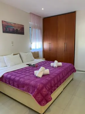 a bedroom with a large bed with purple sheets and wooden cabinets at Cozy Violeta in Ialyssos