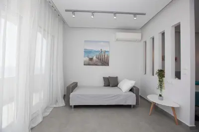 a white room with a bed and a table at The Azure Blue Apt Faliraki in Faliraki