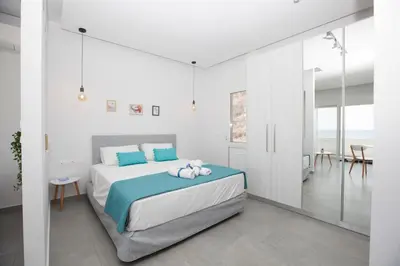 a bedroom with a bed with blue pillows on it at The Azure Blue Apt Faliraki in Faliraki