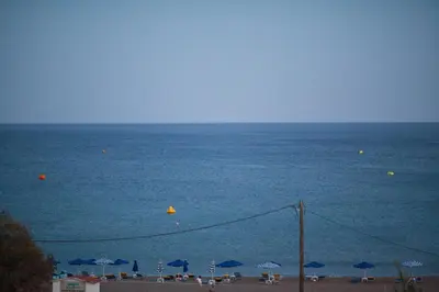 a view of the beach with umbrellas and the ocean at The Azure Blue Apt Faliraki in Faliraki