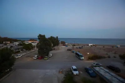 a parking lot with cars parked next to the ocean at The Azure Blue Apt Faliraki in Faliraki