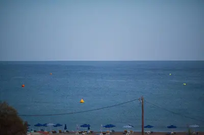 a view of the beach with umbrellas and the ocean at The Azure Blue Apt Faliraki in Faliraki