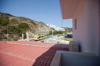 a building with a red roof with a yellow bus at The Azure Blue Apt Faliraki in Faliraki
