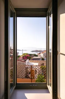 a window with a view of a balcony at Aphrodite Villas Halki - Villa Bougainvillea in Halki