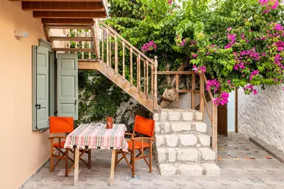a table with chairs and a staircase with flowers at Aphrodite Villas Halki - Villa Bougainvillea in Halki