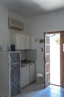 a white kitchen with a refrigerator and a toilet at Barvas studios Lindos in Líndos
