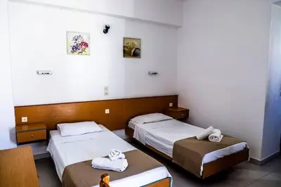 a room with two beds and a table in it at Barvas studios Lindos in Líndos