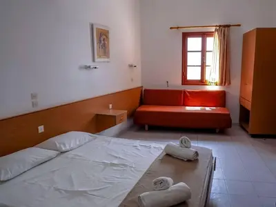 a bedroom with a bed and a red couch at Barvas studios Lindos in Líndos