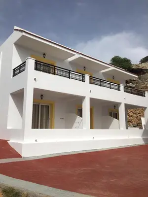 a large white house with a red brick driveway at Coloma Apartments Pefkos in Pefki Rhodes