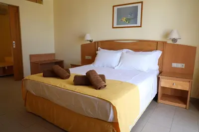 a bedroom with a large bed with two pillows on it at Coloma Apartments Pefkos in Pefki Rhodes
