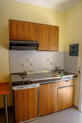 a kitchen with wooden cabinets and a sink at Coloma Apartments Pefkos in Pefki Rhodes