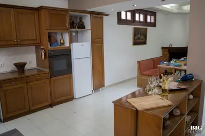 a kitchen with wooden cabinets and a white refrigerator at The BIG one!! in Rhodes Town