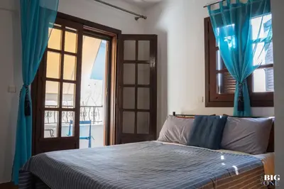 a bedroom with a bed with blue curtains and a window at The BIG one!! in Rhodes Town