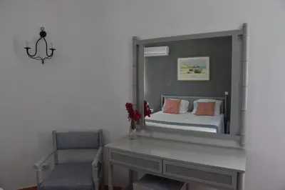 a bedroom with a mirror with a bed and a chair at Boutique Hotel Tilos Mare in Livadia