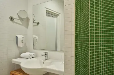 a white bathroom with a sink and a mirror at The Apartments by Esperia in Rhodes Town