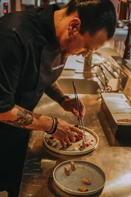a man in a kitchen preparing food on a plate at Cook's Club Ialysos Rhodes in Ialyssos