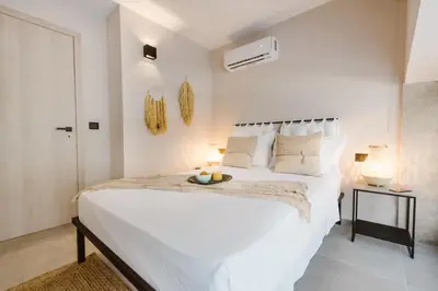 a white bedroom with a large white bed and two lamps at Manolis Loft Apartment, Rhodes Town in Rhodes Town