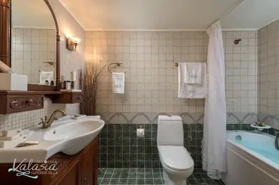 a bathroom with a sink and a toilet and a tub at Panthea Valasia Boutique Villa in Líndos