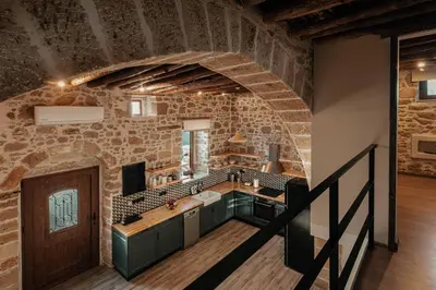a large kitchen with a stone wall and a staircase at La casa dell'arch in Haraki
