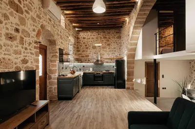 a large kitchen with a brick wall and a tv at La casa dell'arch in Haraki