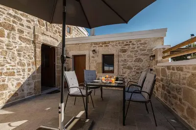 a patio with a table and chairs and an umbrella at La casa dell'arch in Haraki