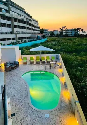 a swimming pool with tables and chairs and a building at White&Blue Beachfront Luxury Suite in Ialyssos