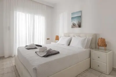 a white bedroom with a large white bed with towels on it at White&Blue Beachfront Luxury Suite in Ialyssos