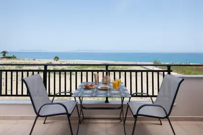 a table and chairs on a balcony with a view of the ocean at White&Blue Beachfront Luxury Suite in Ialyssos