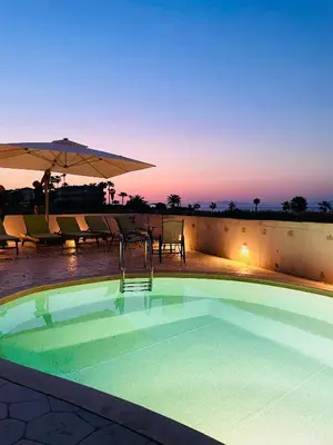 a swimming pool with an umbrella and tables and chairs at White&Blue Beachfront Luxury Suite in Ialyssos