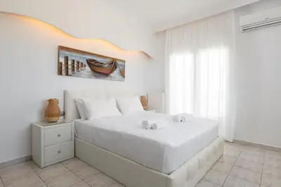 a white bedroom with a bed and a window at White&Blue Beachfront Luxury Suite in Ialyssos
