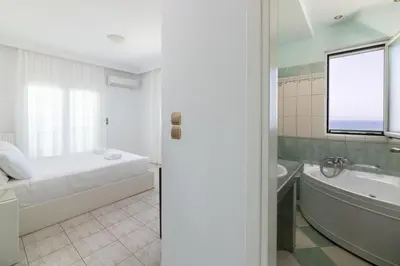 a bedroom with a bed and a tub and a sink at White&Blue Beachfront Luxury Suite in Ialyssos