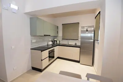 a kitchen with white cabinets and a stainless steel refrigerator at Kameiros Treasure Villa in Kalavárda