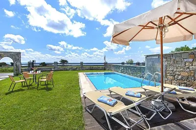 a pool with two chairs and an umbrella and a table and chairs at Holiday home in Kiotari near the beach in Kiotari