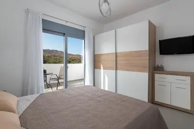 a bedroom with a bed and a television and a balcony at Dama Dama Villas in Gennadi