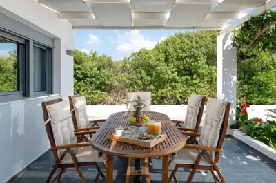 a wooden table and chairs on a patio at Dama Dama Villas in Gennadi