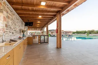 an outdoor kitchen with a pool in the background at Ktima Kritikos in Paradeísion