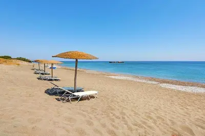 a row of chairs and umbrellas on a beach at Holiday home in Kiotari with a terrace or balcony in Kiotari