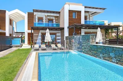 a villa with a swimming pool in front of a house at Holiday home in Kiotari with a terrace or balcony in Kiotari