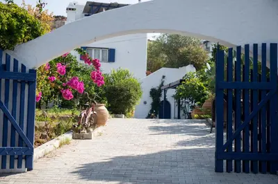 an archway with a blue fence and pink flowers at Nefeli house in Archangelos