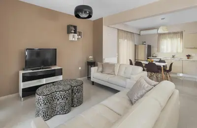 a living room with a white couch and a tv at La Maisonette - 4 bedroom villa near the beach in Ialyssos